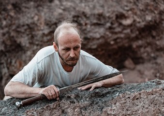 Warlike wanderer in the mountains resting after a battle with a dagger in his hand