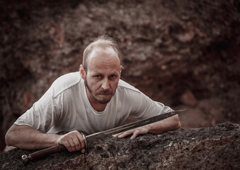 Warlike wanderer in the mountains resting after a battle with a dagger in his hand