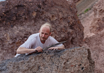 Warlike wanderer in the mountains resting after a battle with a dagger in his hand