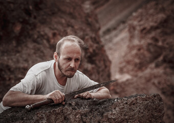 Warlike wanderer in the mountains resting after a battle with a dagger in his hand
