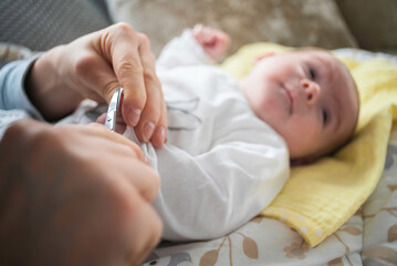 Mother trimming newborns nails on a bed.