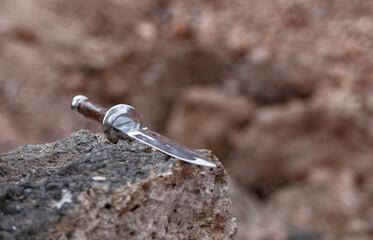A sharp dagger close up lying on a rock after the battle