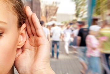 A woman holds hand near her ear and listening to something