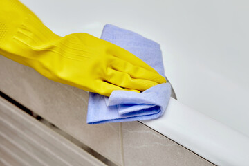 Wash the edge of the white bath. Professional housekeeping. Gloves for cleaning.