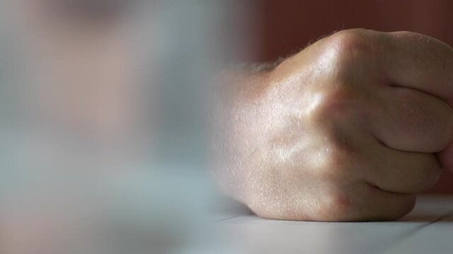Man strikes fist on table in anger. Domestic violence. Close up. Slow pan.