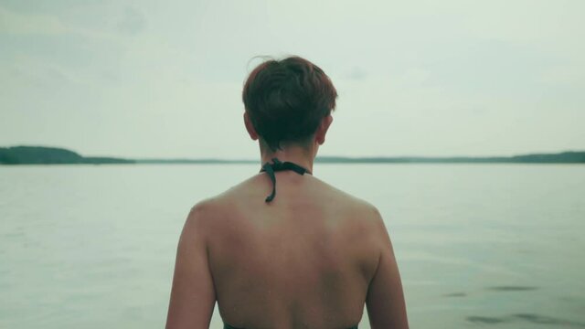 Close up back shot of short hair women walking deep into the lake water