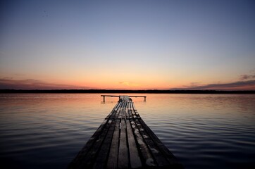 Fototapeta na wymiar orange sunset on a lake and wooden pier