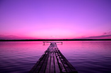 purple sky and pier on a lake at sunset