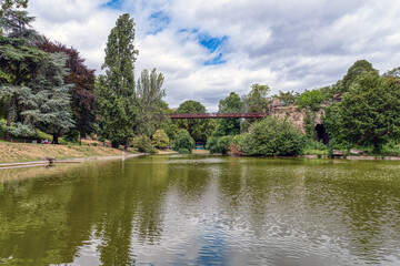 Lake in the Parc Buttes-Chaumont with footbridge in the background - Paris, France