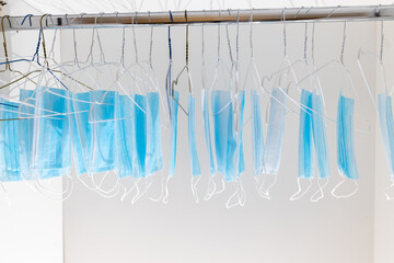 Disposable surgical masks hanging on hangers in a wardrobe closet. Concept of new normal. Concept...