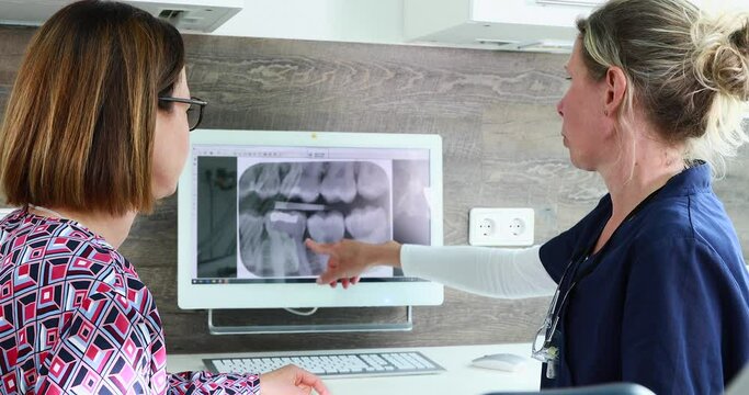 Female dentist explaining x-ray image to female patient