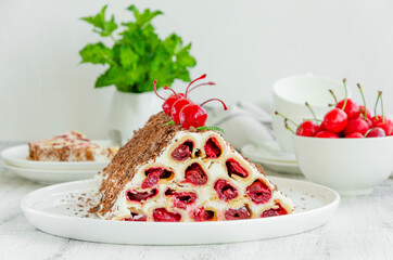Homemade cake with cherries, sour cream and chocolate on a white plate on a wooden background. Horizontal, copy space.