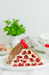 Homemade cake with cherries, sour cream and chocolate on a white plate on a wooden background. Vertical, copy space.