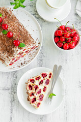 Homemade cake with cherries, sour cream and chocolate on a white plate on a wooden background. Vertical, copy space.