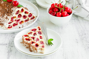 Homemade cake with cherries, sour cream and chocolate on a white plate on a wooden background. Horizontal, copy space.