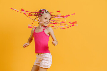 Stylish girl with pink dreadlocks posing in bright clothes on a yellow background. Beauty, fashion.