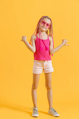 Stylish girl with pink dreadlocks posing in bright clothes on a yellow background. Beauty, fashion.