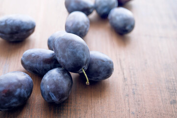 Fototapeta na wymiar Sweet juicy blue plums on a brown wooden old surface close-up, soft focus
