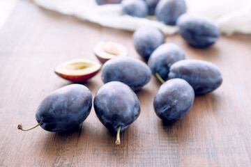 Obraz na płótnie Canvas Sweet juicy blue plums on a brown wooden old surface close-up, soft focus