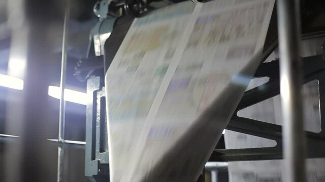 Newspapers moving fast in a printing press factory.