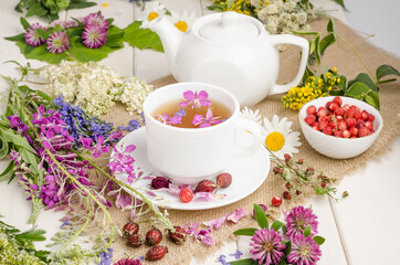 Herbal tea in a white cup with flowers. Tea ceremony. Tea with chamomile, with wild rose and clover
