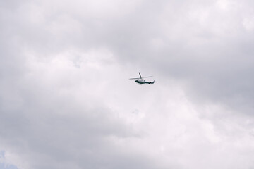Passenger helicopter flies in the sky among the clouds.
