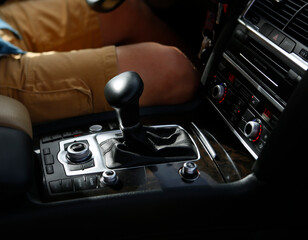 Inside car salon, view of manual gearbox and speed stick and driver man with black and beige leather decor  