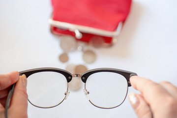 look through the glasses at the wallet, the coins are blurred, out of focus, the concept of a small pension, poor vision in old age, you need to check visual acuity