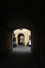Obraz premium view of the entrance courtyard with a high arch, iron gates and parked cars