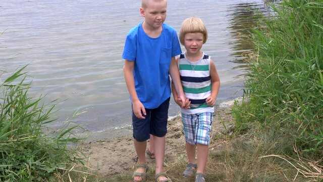 Three boys play and jump on riverbank. Children are happy to go out after quarantine.