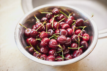 washing ripe cherry berries indoors domestik kitchen. water cleaning fruits. healthy eating and wellness concept.