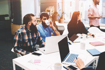Fototapeta premium Group of diverse designers brainstorming having a meeting in an open plan coworking office. Young team of experienced professionals planning the development of new successful startup project