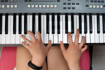 Hands of a girl on the keyboard of a piano