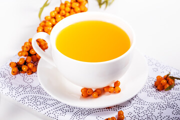Tea of sea-buckthorn berries with honey and a branch on bright background