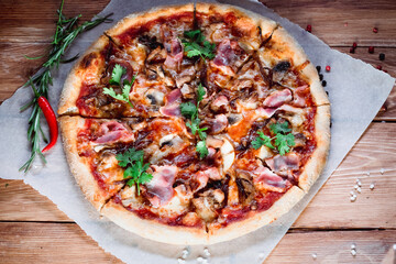 Appetizing pizza on a wooden table surrounded by herbs and spices. The concept of delicious food, restaurants and cafes