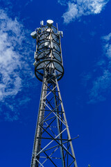 Mobilfunkmast unter blauem HImmel, mit Antennen für Mobilfunk, Digitalfunk, Richtfunk; Freifläche...