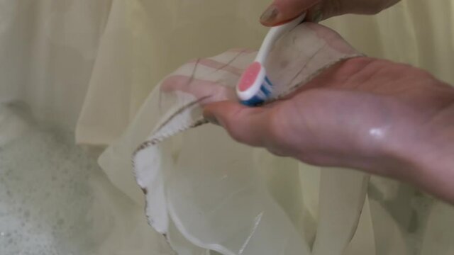 Female hands scrubbing dirty lace wedding dress with a toothbrush