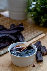 Carob molasses and carob pods on wooden background