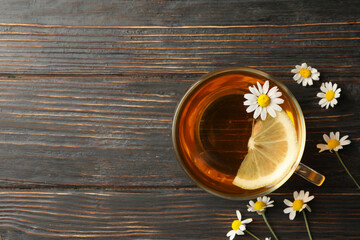 Cup of chamomile tea on wooden background, top view