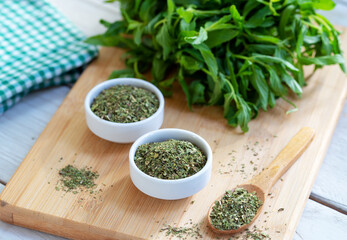 Dried peppermint in a white bowl and a bunch of fresh mint, on wooden background. Food background.