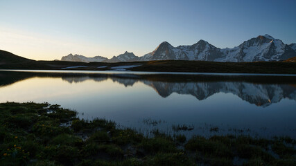 Eiger, Mönch und Jungfrau während Sonnenaufgang mit Spiegelung in Bergsee, Schweiz