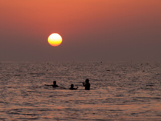 people bathing on the beach with sunset