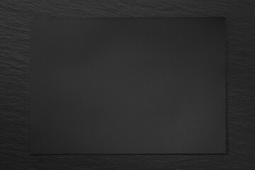 Black paper on a black slate background. 