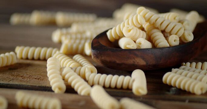 The dry fusilli pasta on the table and spoon rotates slowly.