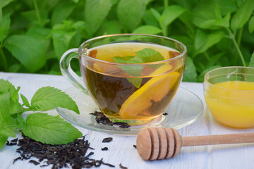 Cup of fragrant mint black tea with honey on a light background