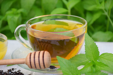Cup of fragrant mint black tea with honey on a light background