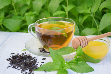 Cup of fragrant mint black tea with honey on a light background