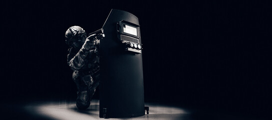 Portrait of a special forces unit fighter. He hides behind a bulletproof shield. Black background....