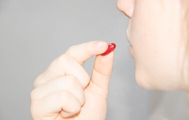  little dude drinks a pill on a white background. tablet near the lips