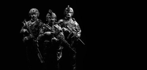 Three soldiers in uniform with a weapon in their hands are looking menacingly.